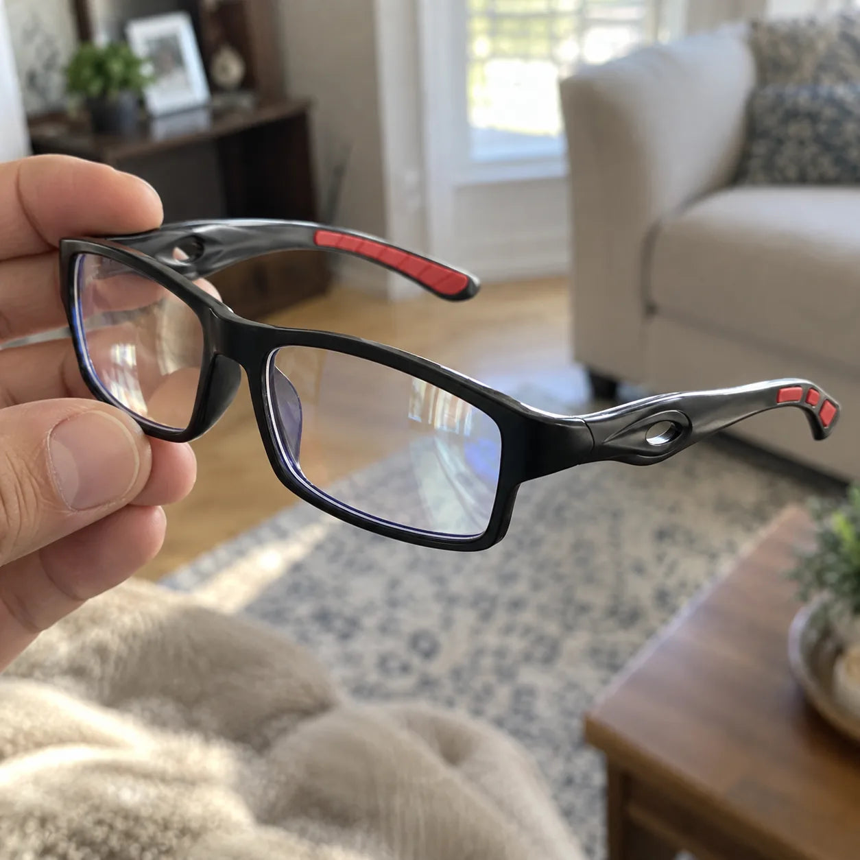 Customer holding black and red reading glasses at home