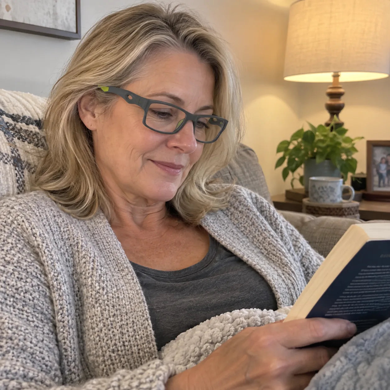 Woman wearing grey and green glasses while reading on a sofa
