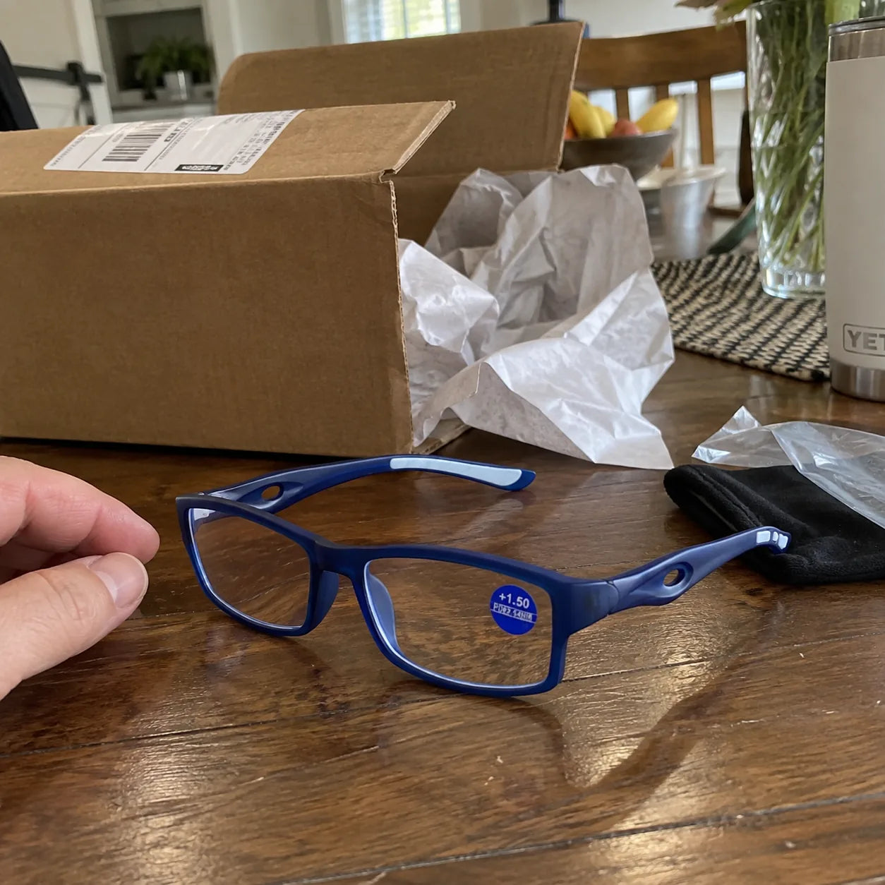 Blue reading glasses after unboxing on a dining table